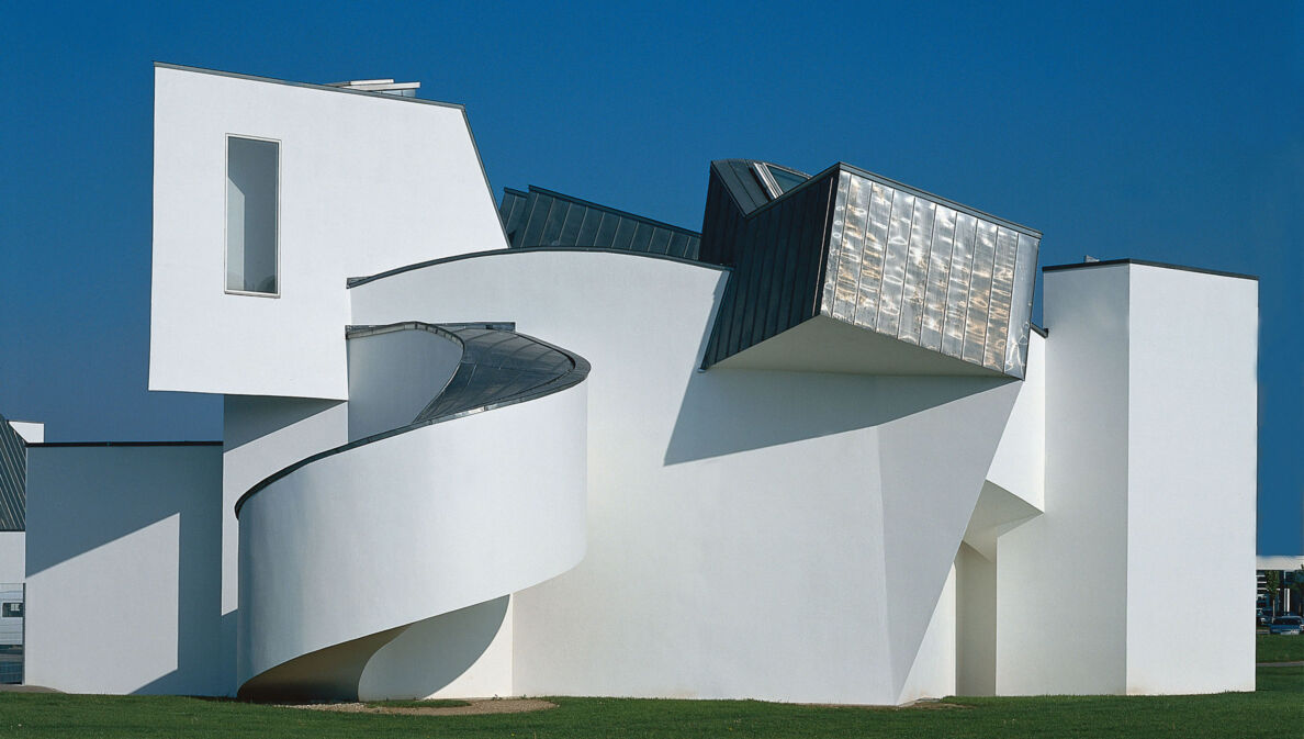 Ein weißes, architektonisch verspieltes Gebäude auf einer grünen Wiese.