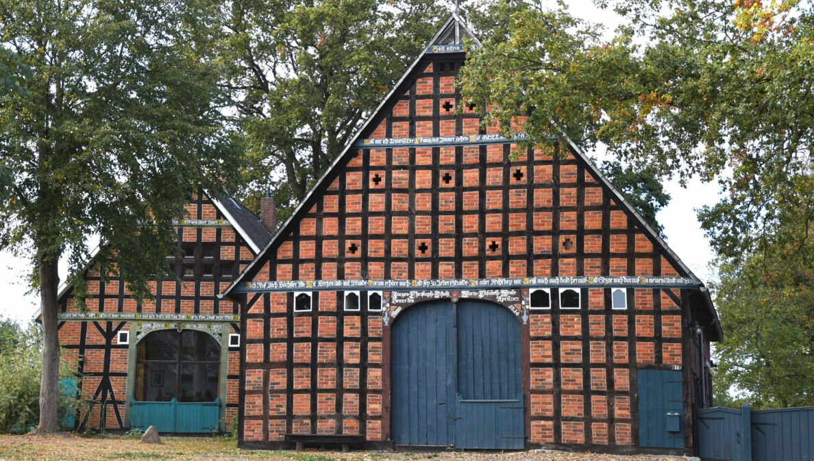 Zwei Fachwerkhäuser mit blauen Toren, daneben Bäume