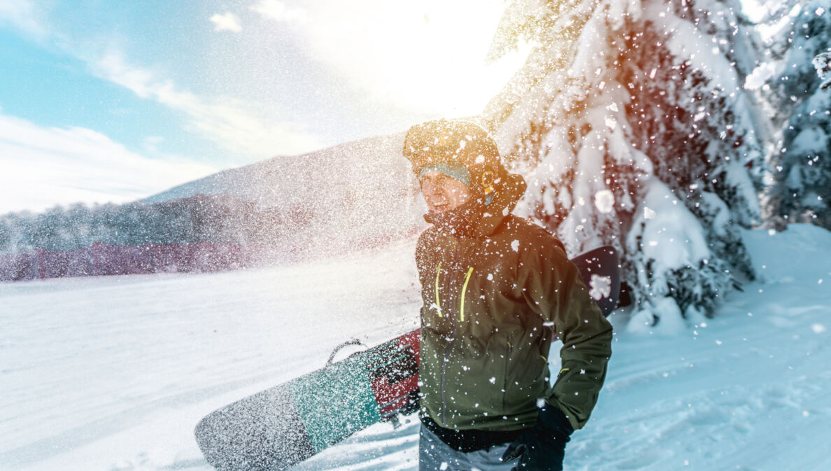 Ein junger Mann mit einem Snowboard unter dem Arm