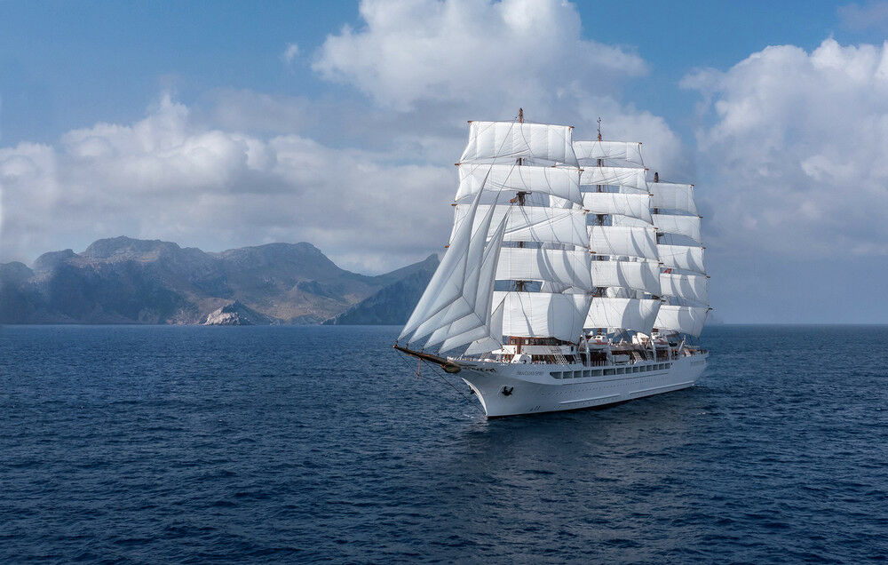 Großes Segelschiff auf dem Meer, im Hintergrund Berge