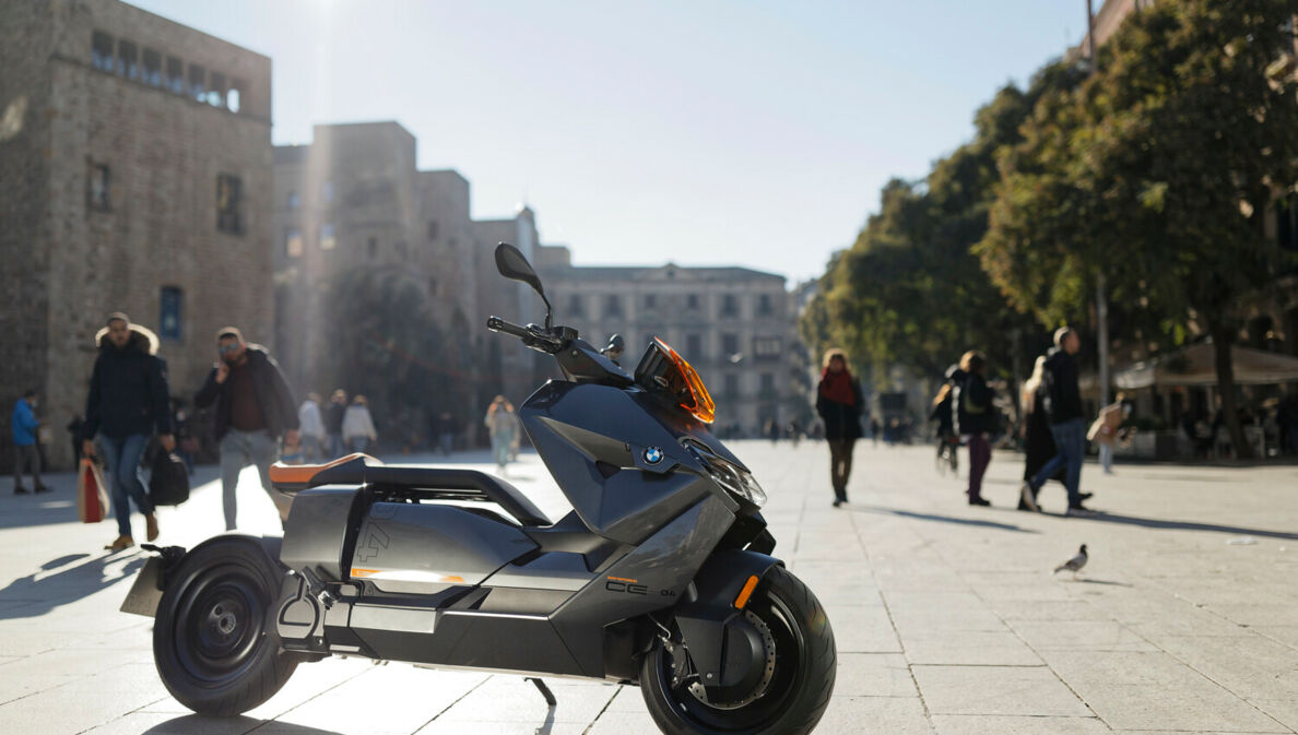 Ein grauer BMW CE 04 parkt vor Palmen in einem Fußgängerbereich.