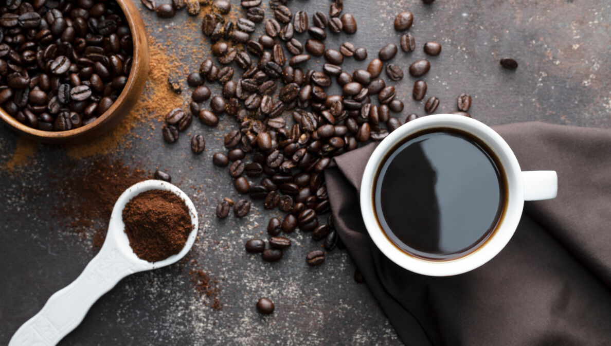 Kaffeebohnen, gemahlener Kaffee und eine Tasse Kaffee von oben fotografiert.