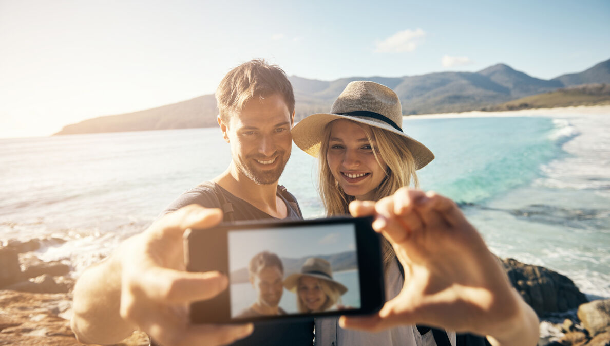 Frau und Mann machen ein Selfie am Strand