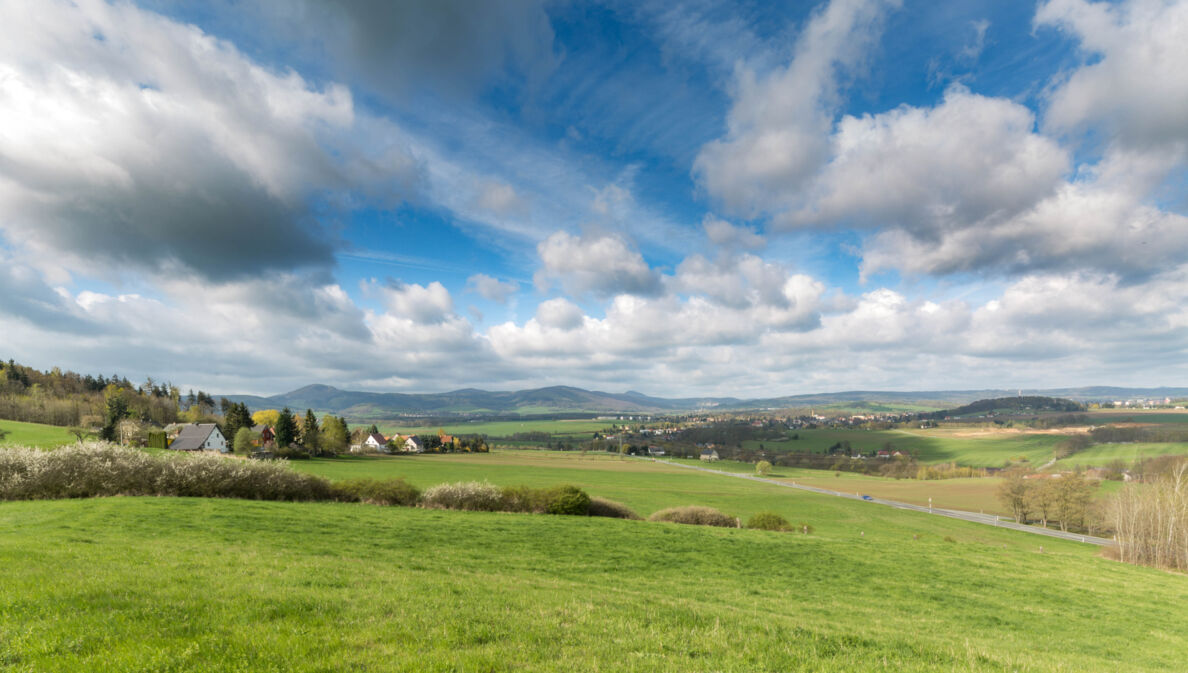 Blick auf eine sommerliche Landschaft mit Wiesen und Bergen