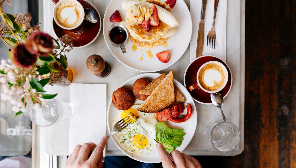 Aufsicht eines gedeckten Tisches mit Kaffeetassen und Speisen zum Brunchen