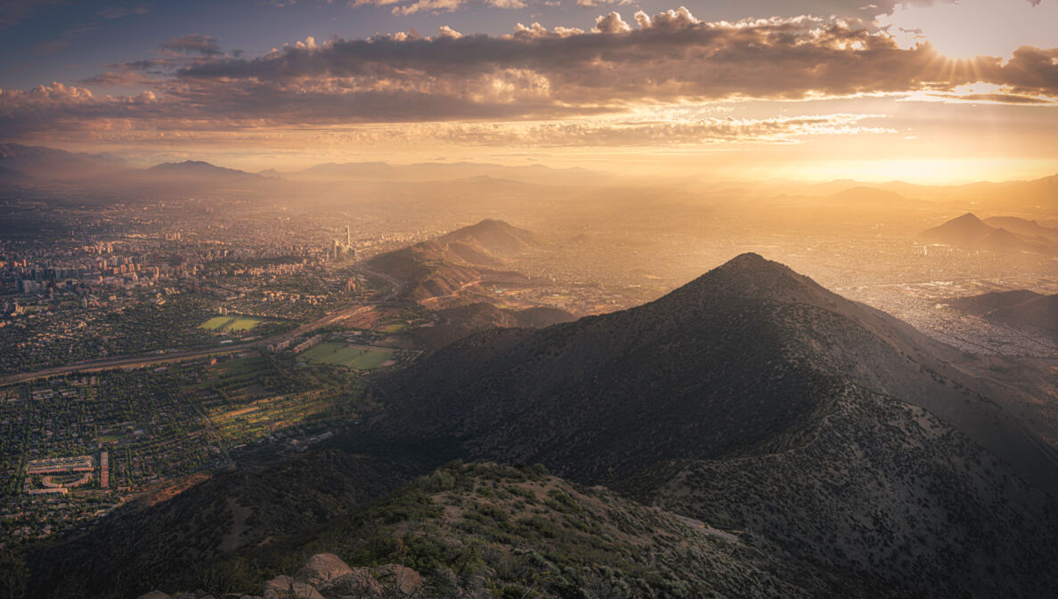 Luftbild von Santiago de Chile mit Sonne hinter Wolken