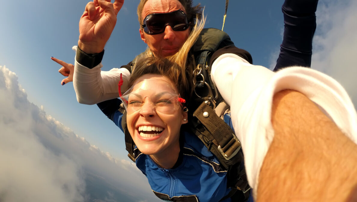 Ein Mann und eine fröhliche Frau beim Tandem-Fallschirmspringen.