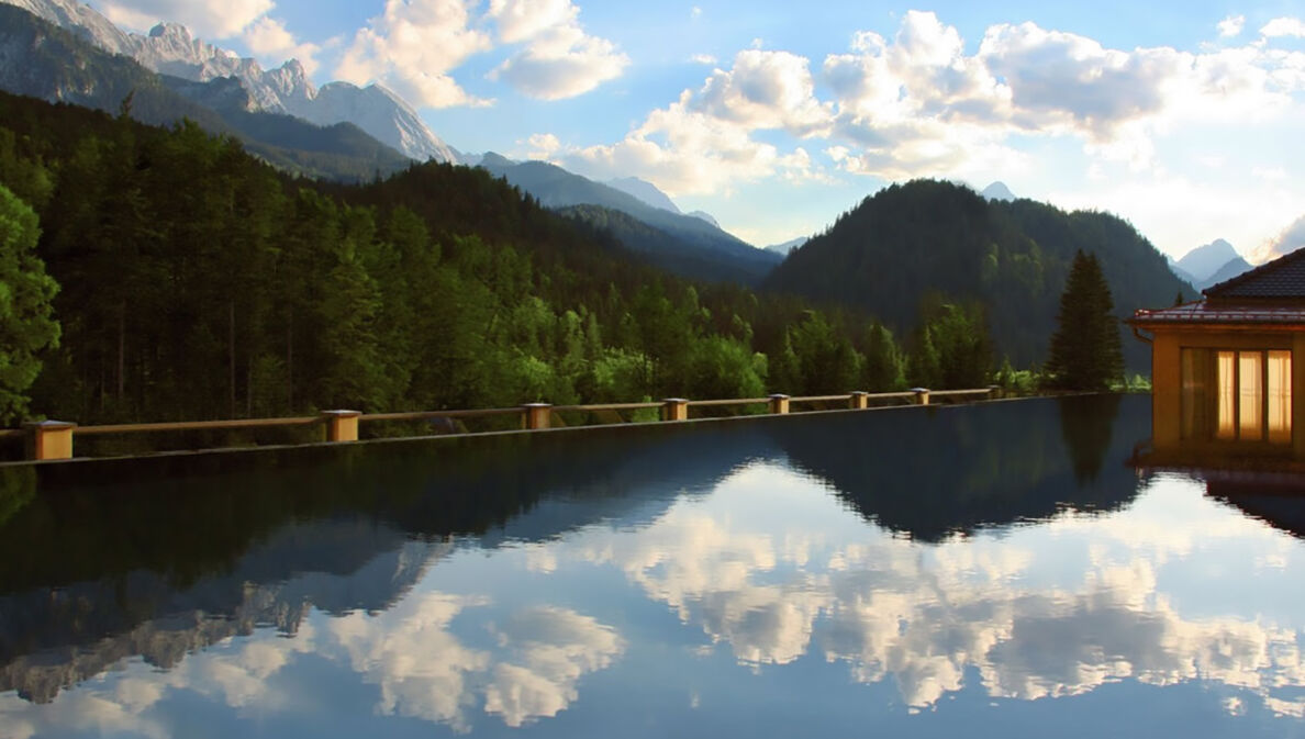 Ein großer Außenpool vor Wald- und Bergpanorama