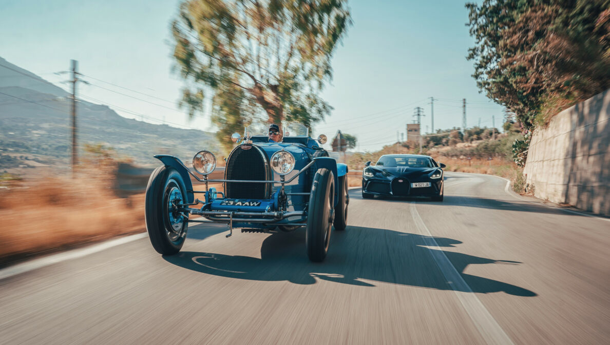 Ein Oldtimer und ein moderner Sportwagen auf einer Straße