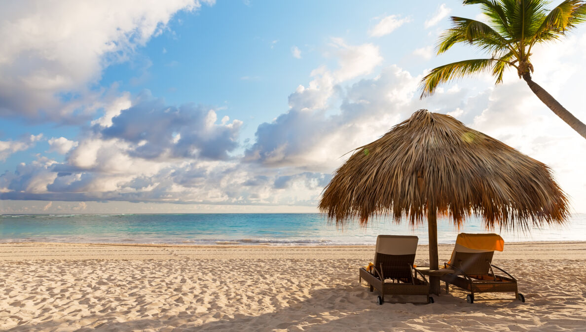 Zwei Liegen unter einem Sonnenschirm am Strand