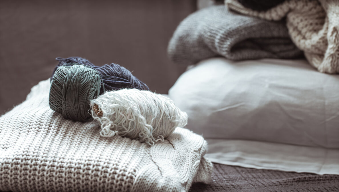 Arrangement aus mehreren Garnknäulen auf einem Strickpullover.