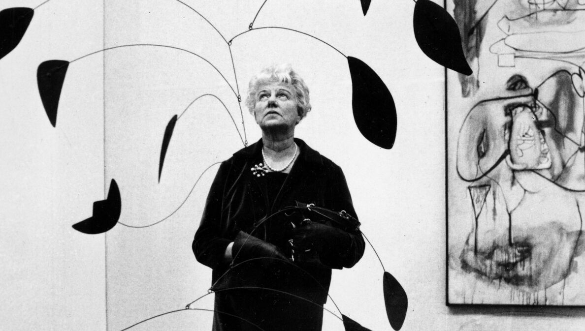 Porträt von Peggy Guggenheim, die in einer Kunstausstellung ein Mobile betrachtet