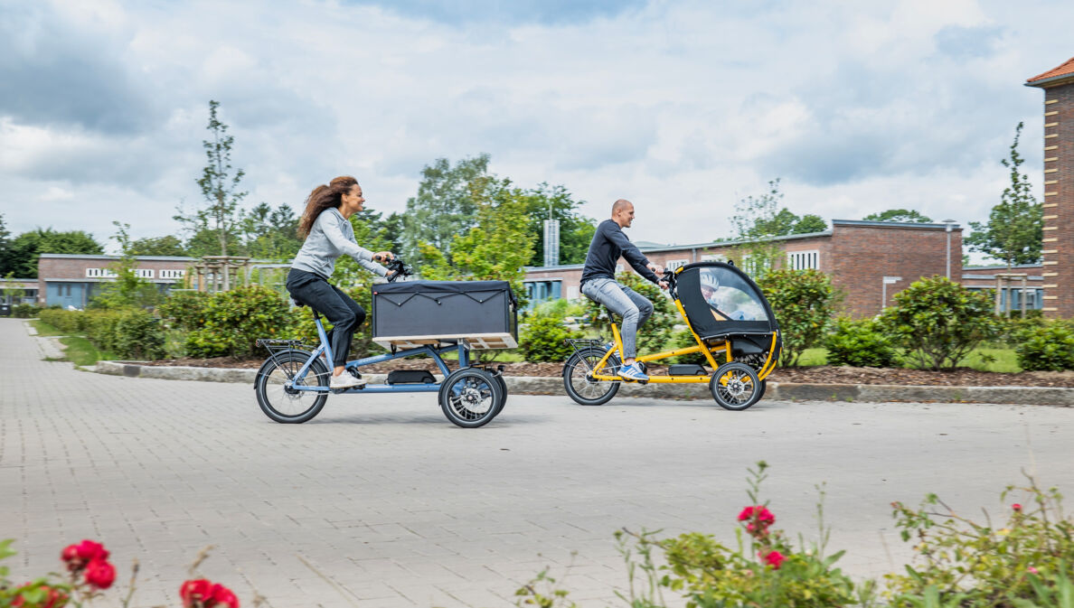 Ein Mann und eine Frau fahren auf zwei Lasten-E-Bikes