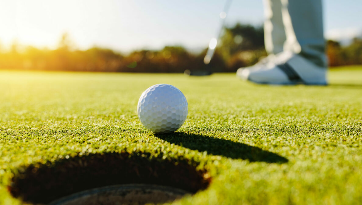 Nahaufnahme eines Golfballs vor dem Loch auf einem Putting-Green