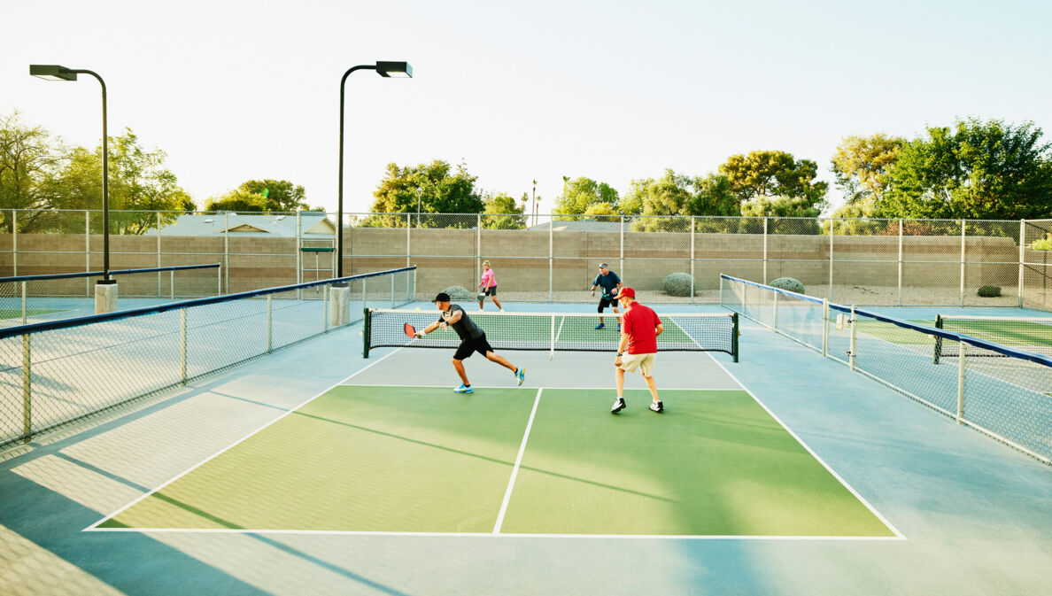 Vier Spieler bei einem Pickleball-Match auf einem Tennishartplatz unter freiem Himmel