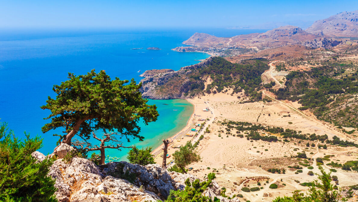 Blick von einem Berg auf einen Strand und hellblaues Wasser