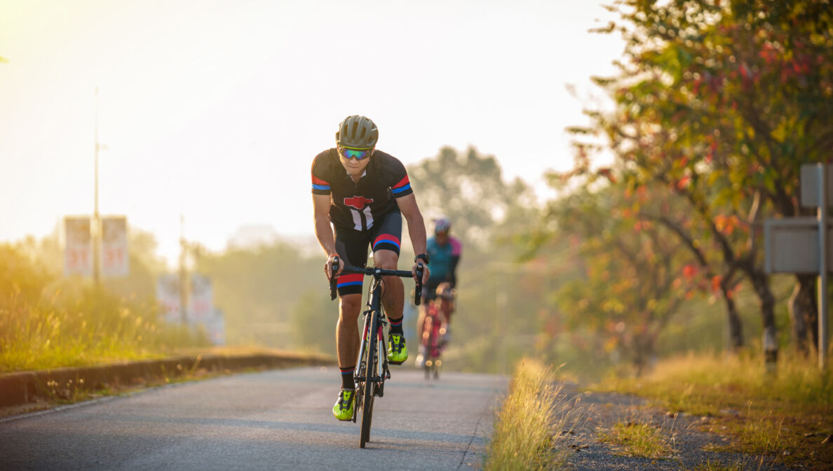 Zwei Rennradfahrer auf einer Straße im Abendlicht