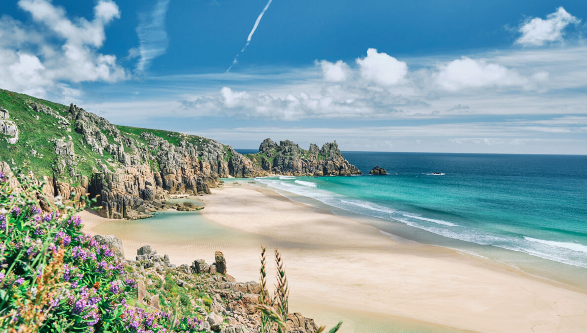 Blick auf die Küste von Cornwall mit Sandstrand, kristallblauem Wasser und Felsvorsprüngen