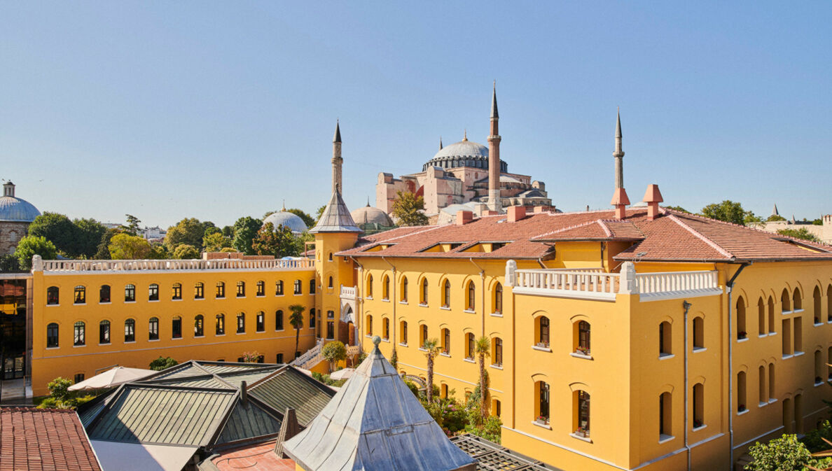 Ein gelbes, neoklassizistisches Gebäude mit Innenhof und einer Moschee im Hintergrund