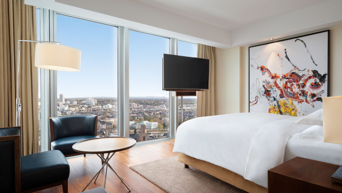 Eine moderne, helle Hotelsuite mit bodentiefen Fenstern und Panoramablick auf Frankfurt am Main