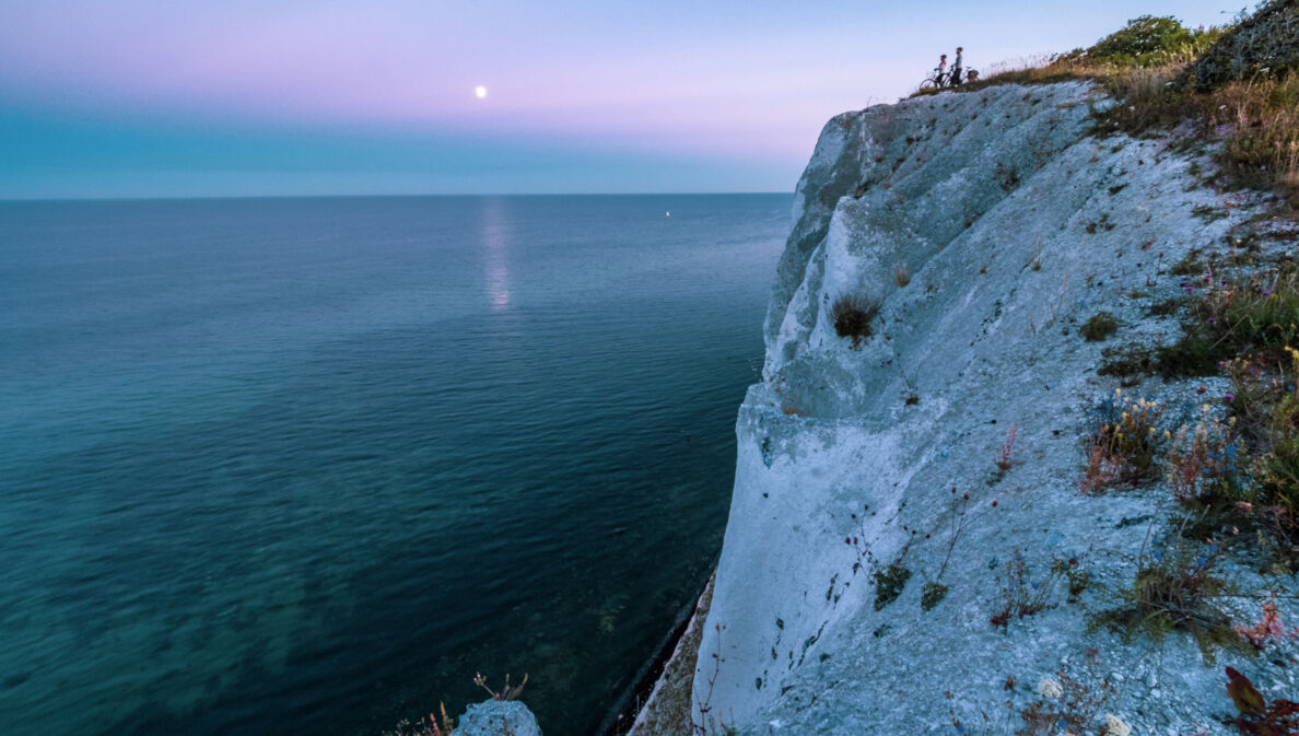 Zwei Radfahrende stehen an den Klippen von Møns Klint und schauen aufs Meer