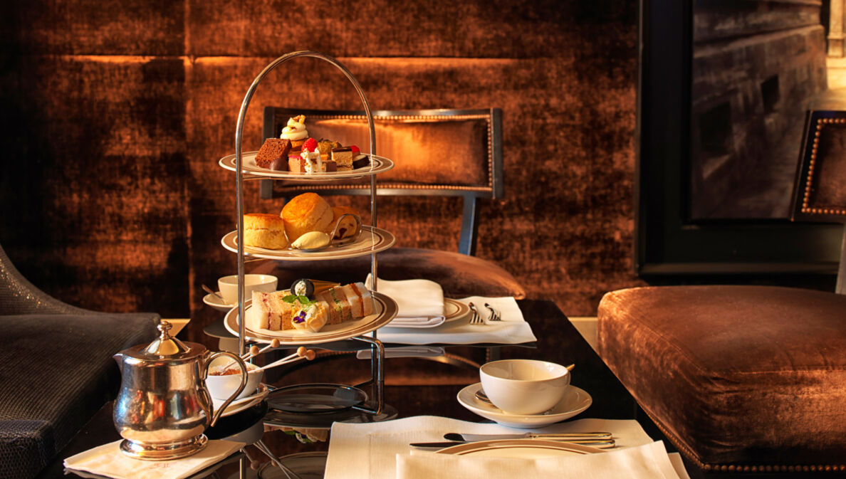 Eingedeckter Tisch zur Teatime mit Gebäck und Süßspeisen auf einer Etagere.