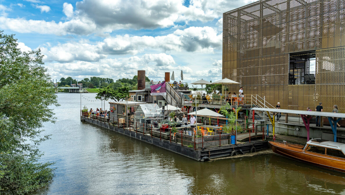 Ein Außencafé neben einem goldenen Pavillon auf einem Ponton.