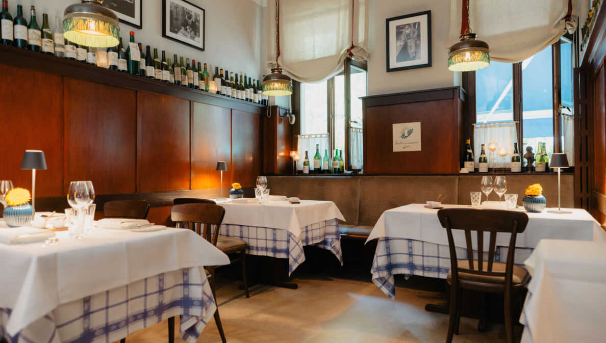 Gemütlicher Speiseraum mit Holzverkleidung und eingedeckten Tischen in einer Brasserie.