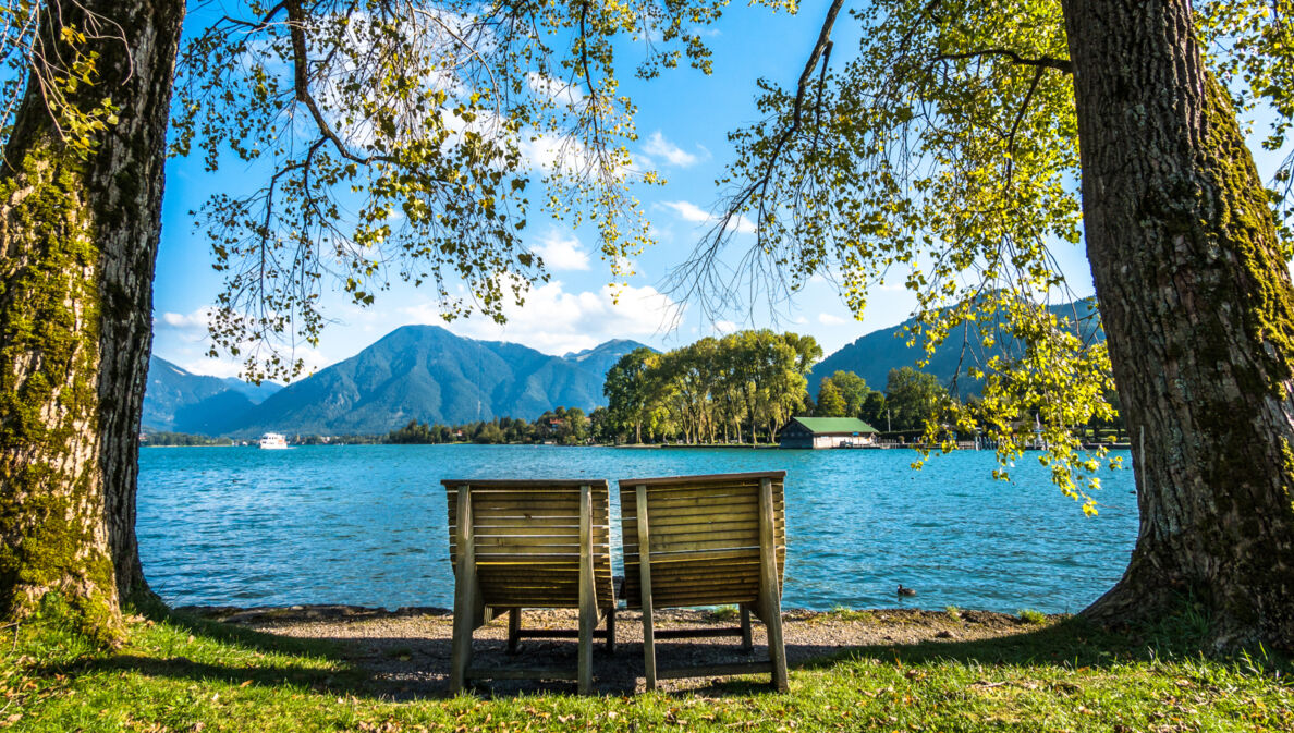 Zwei Holzliegen am Ufer des Tegernsees.