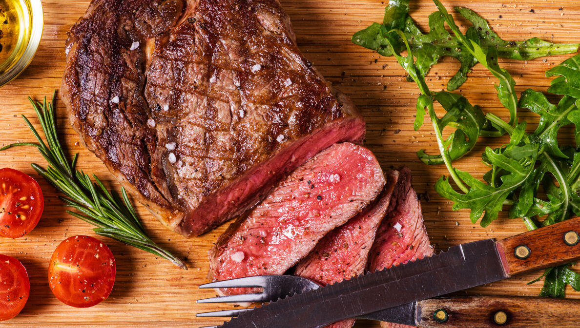 Aufsicht eines gebratenen, angeschnittenen Steaks auf einem Holzbrett.