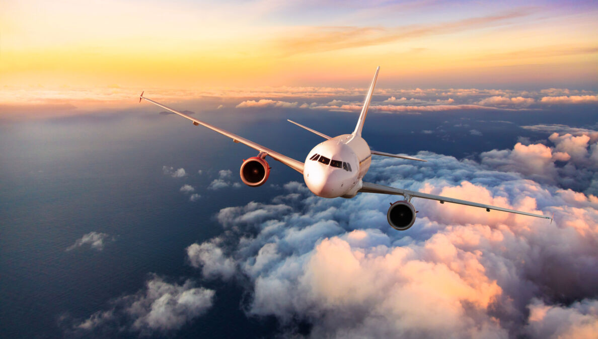 Ein Flugzeug fliegt über den Wolken bei Sonnenuntergang.