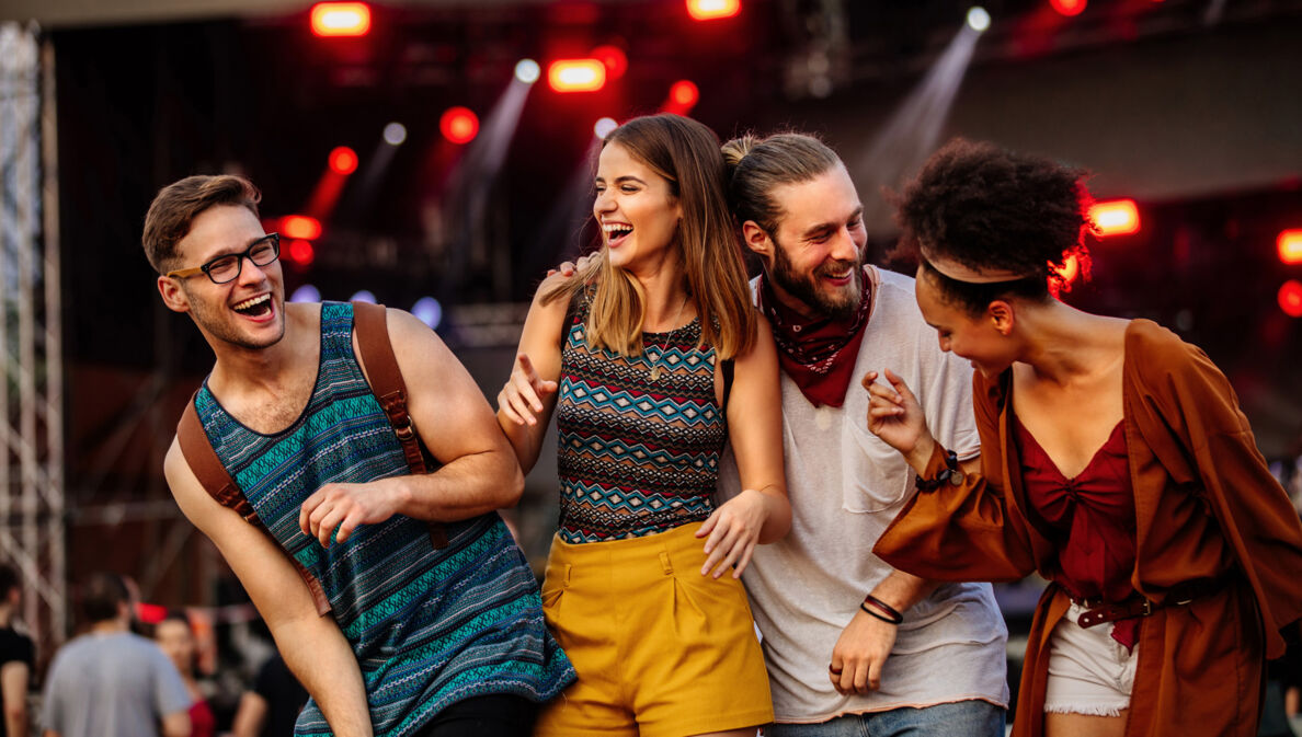 Vier gut gelaunte, junge Menschen auf einem Festival.