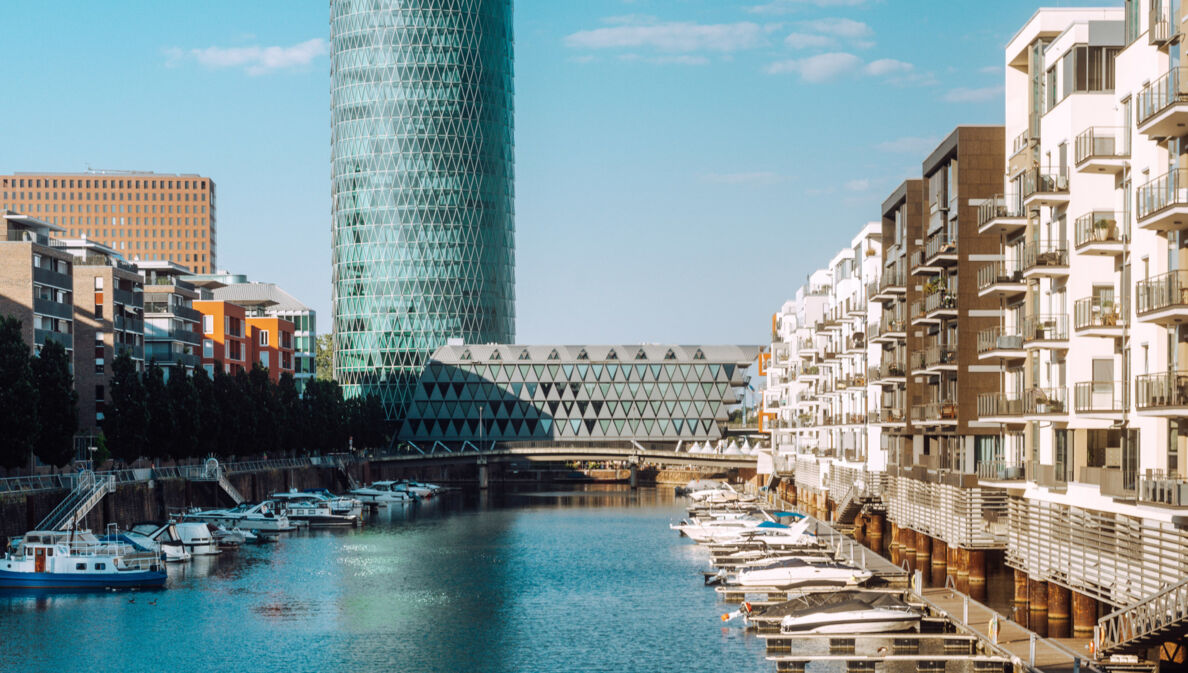 Binnenhafen mit Booten vor Wohnhäusern und einem modernen Gebäudekomplex.