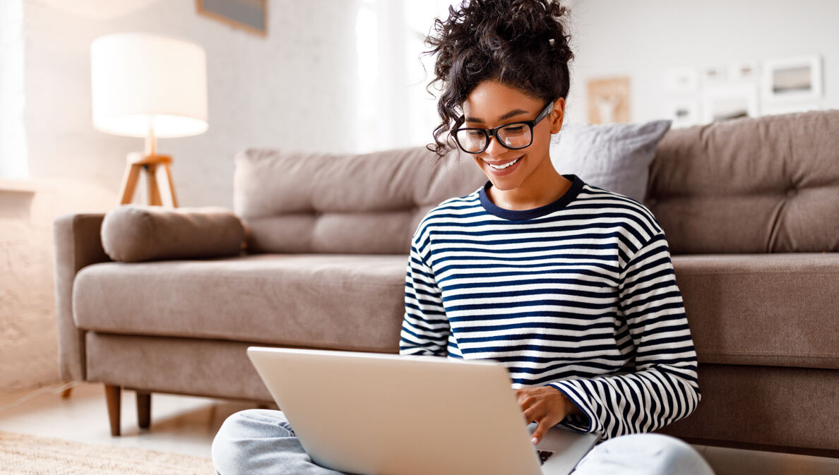 gut gelaunte Frau sitzt zuhause am Laptop