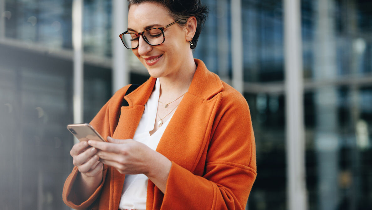 Elegante Geschäftsfrau schaut auf ihr Smartphone