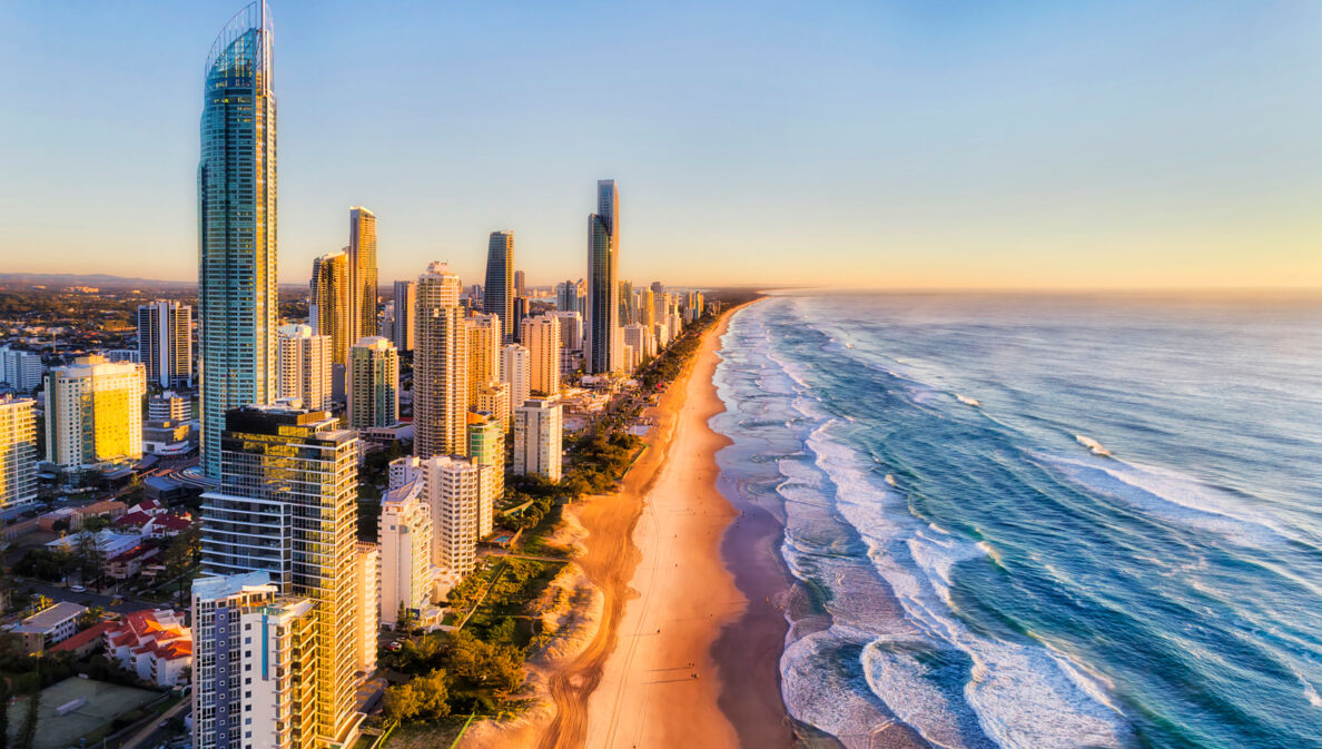 Luftaufnahme der Skyline von Surfers Paradise am kilometerlangen Sandstrand bei goldenem Sonnenlicht.