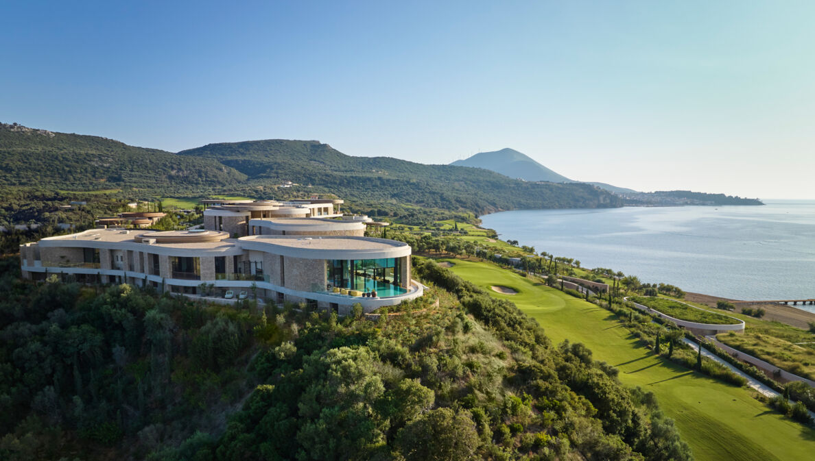 Hotelanlage inmitten einer grünen Hügellandschaft am Meer.