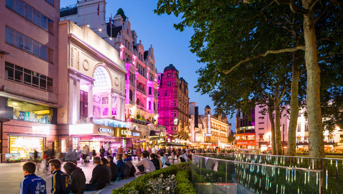 Belebter Leicester Square mit beleuchteter Häuserfassade am Abend.