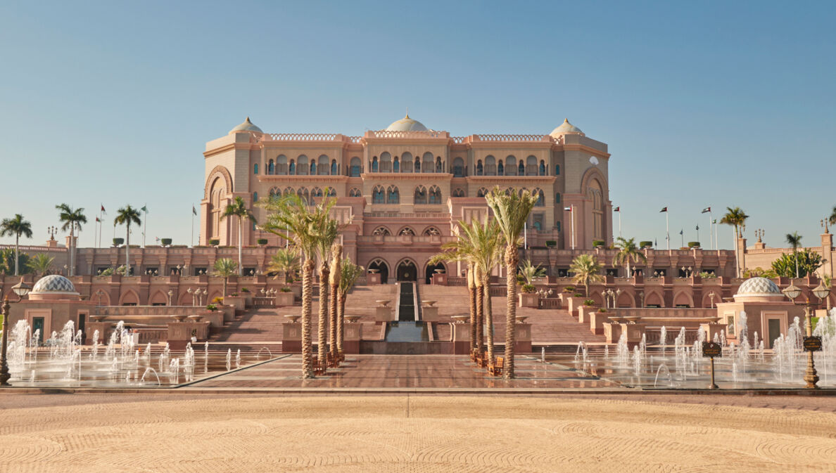 Außenansicht des Emirates Palace Mandarin Oriental Hotels in Abu Dhabi mit Palmen und Brunnen im Vordergrund.