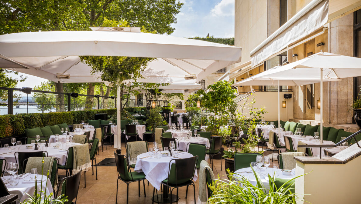 Terrasse eines gehobenen Restaurants mit eingedeckten Tischen.