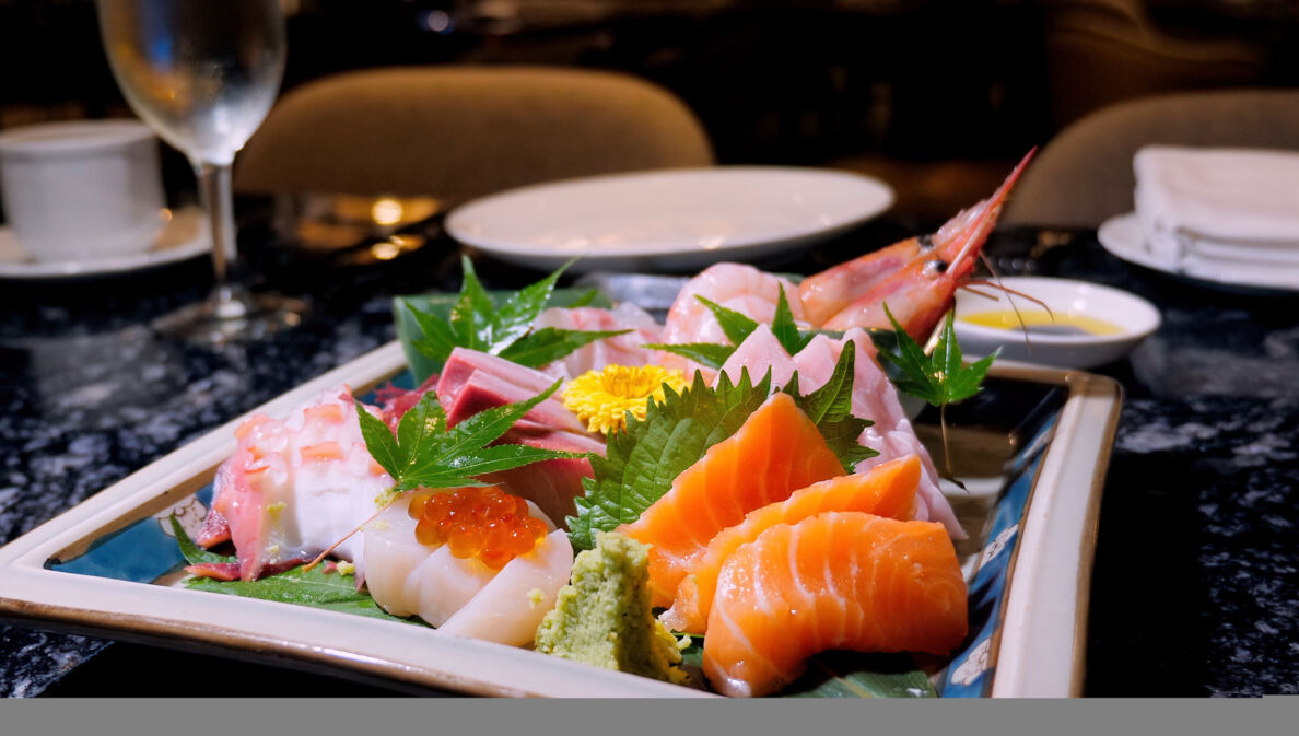 Verschiedene Sashimi Sushi und Scampi auf einem dekorierten Teller in einem Restaurant.