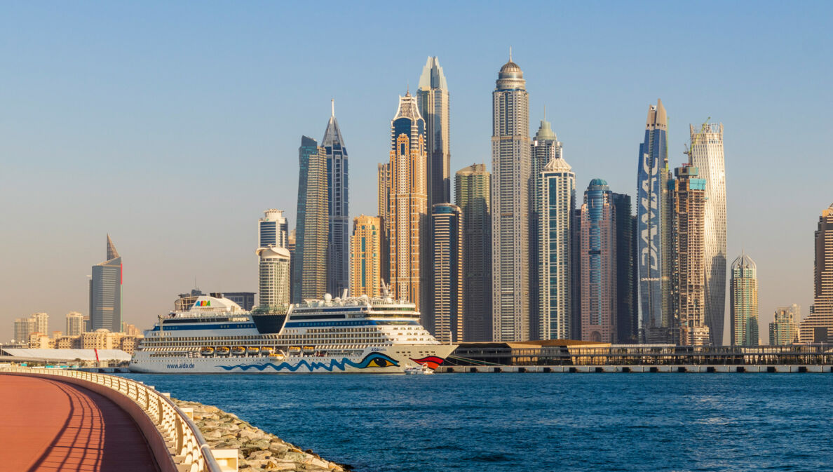 Ein AIDA Kreuzfahrtschiff vor der Skyline Dubais.