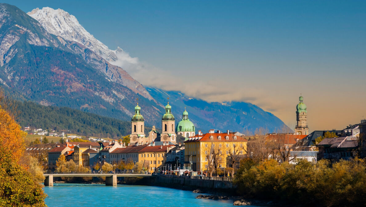 Skyline der Innsbrucker Altstadt am Fluss vor Bergpanorama.