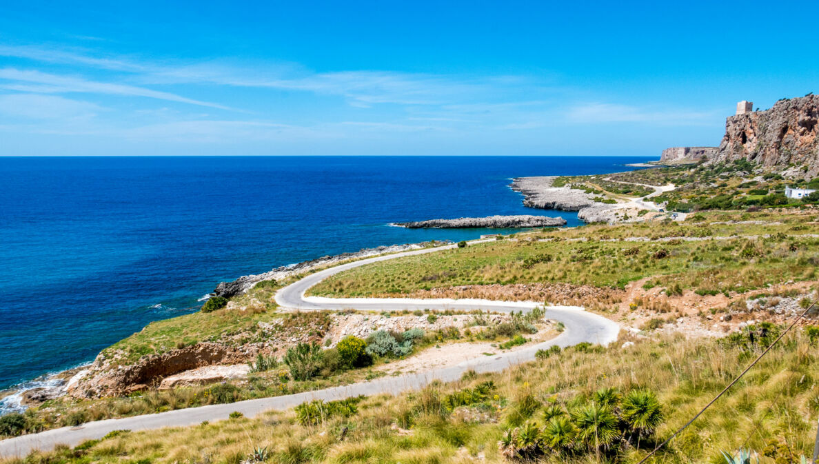 Kurvige Küstenstraße in mediterraner Landschaft.