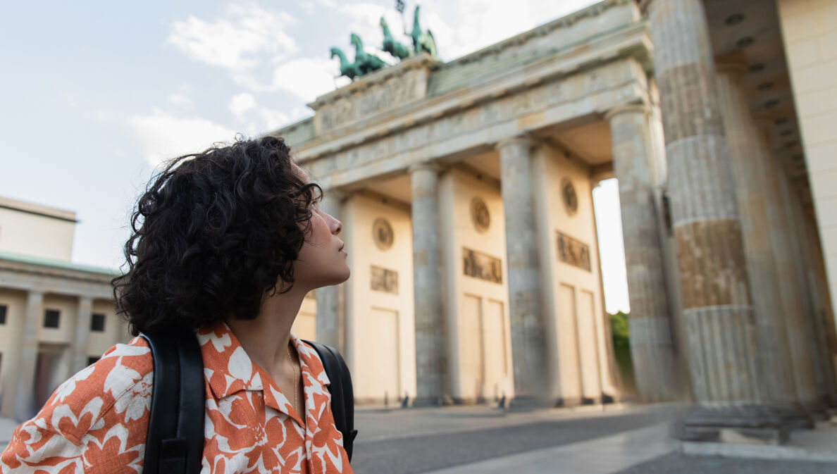 Eine junge Frau schaut auf das Brandenburger Tor