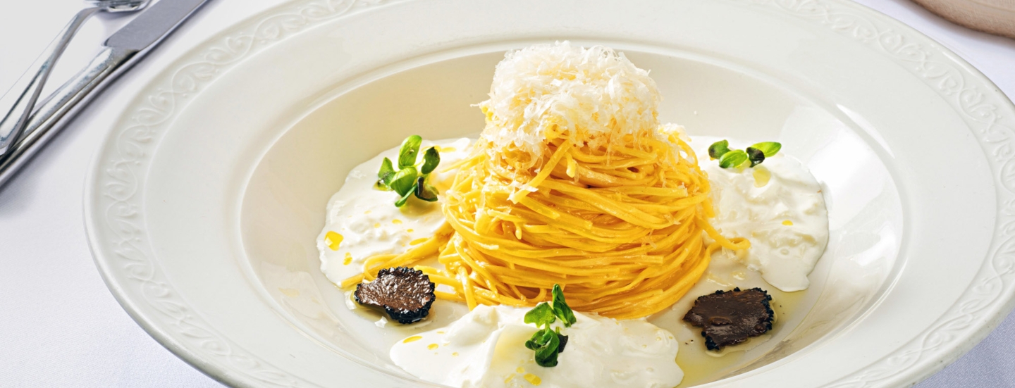 Spaghetti-Gericht mit Burrata und Trüffel, edel angerichtet auf einem weißen Teller.