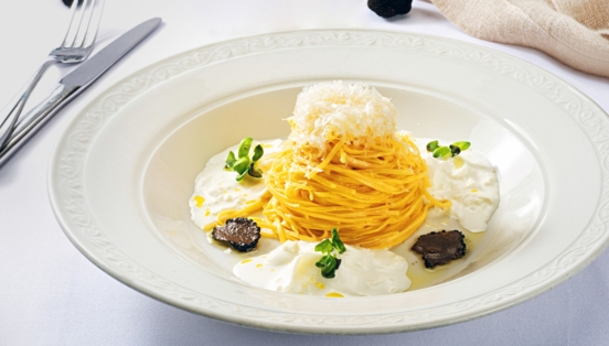 Spaghetti-Gericht mit Burrata und Trüffel, edel angerichtet auf einem weißen Teller.