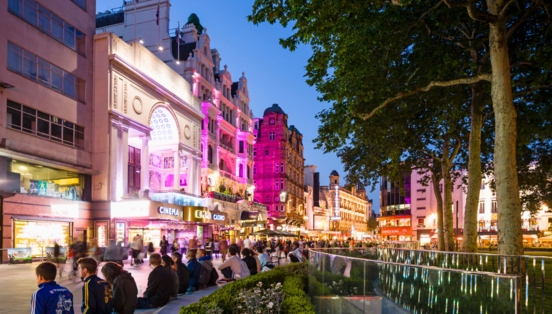 Belebter Leicester Square mit beleuchteter Häuserfassade am Abend.