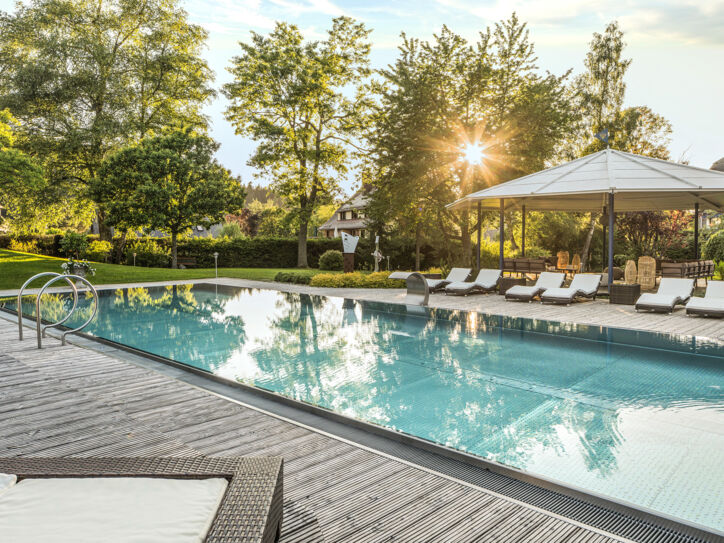 Elegante Terrasse mit Außenpool und Liegestühlen in begrünter Umgebung