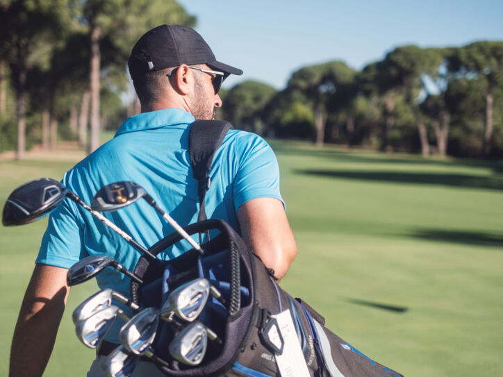 Golfspieler mit Golftasche läuft über einen Golfplatz